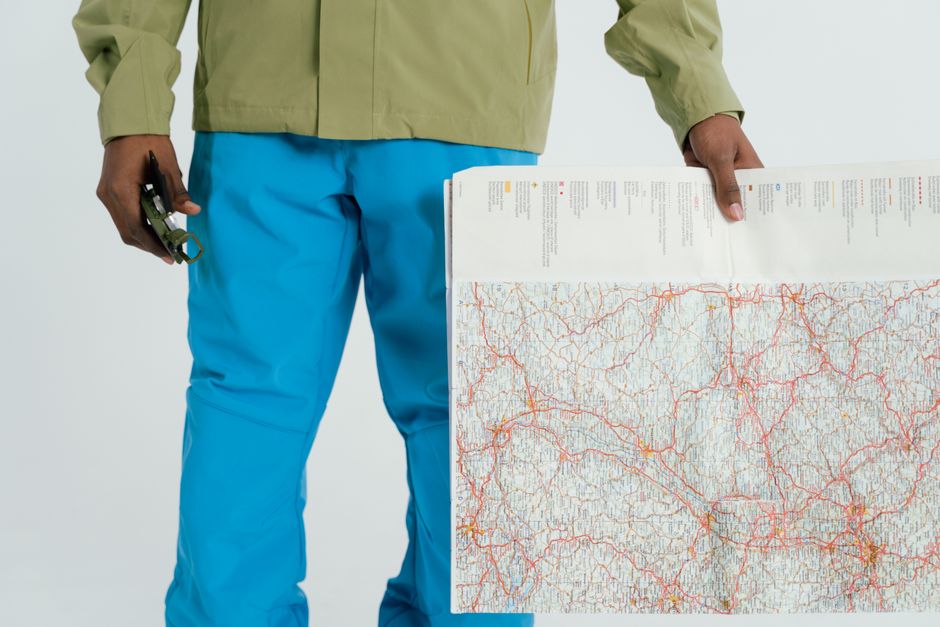 Man in outdoor attire holding a map and compass, prepared for exploration.