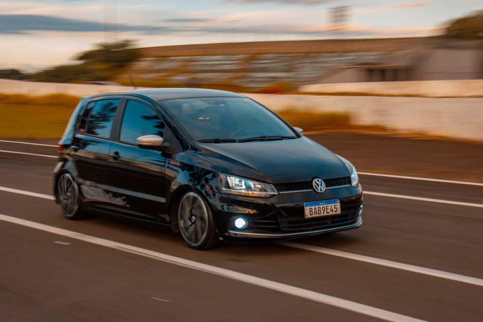 Black Volkswagen hatchback speeding on road, showcasing dynamic motion blur on a clear day.